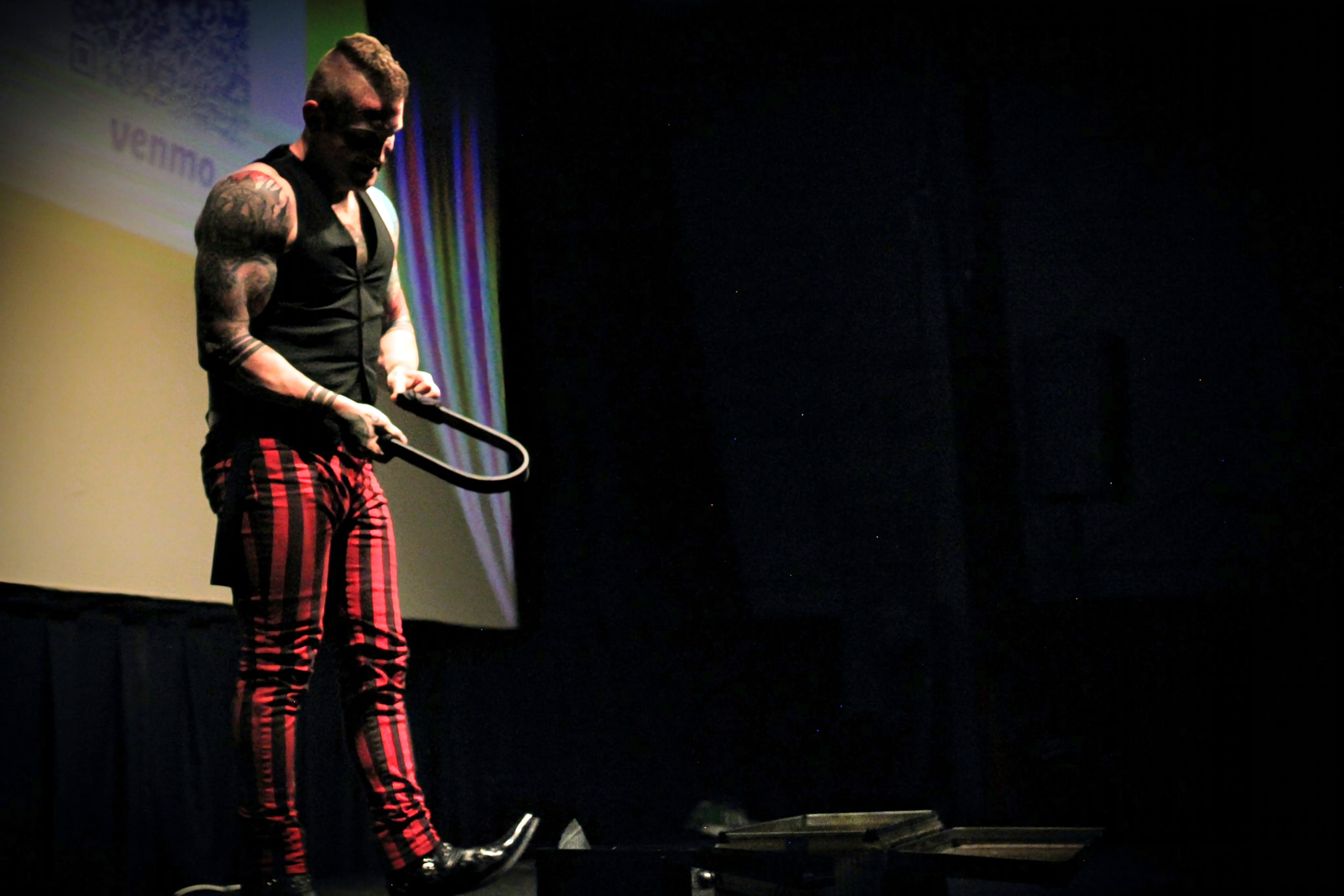 Reid Wilson bending steel horseshoe during circus strongman stage performance