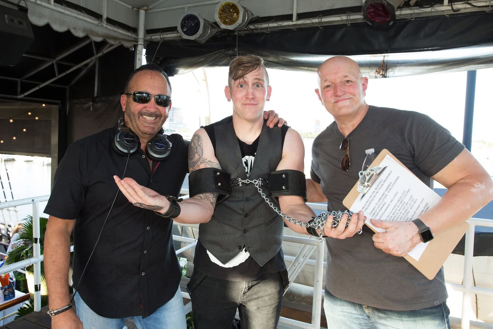 Reid Wilson with DJ and event host, wearing chains and leather cuffs at outdoor event