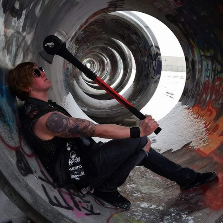 Reid Wilson posing with bent steel barbell in graffiti-covered tunnel, dramatic perspective shot