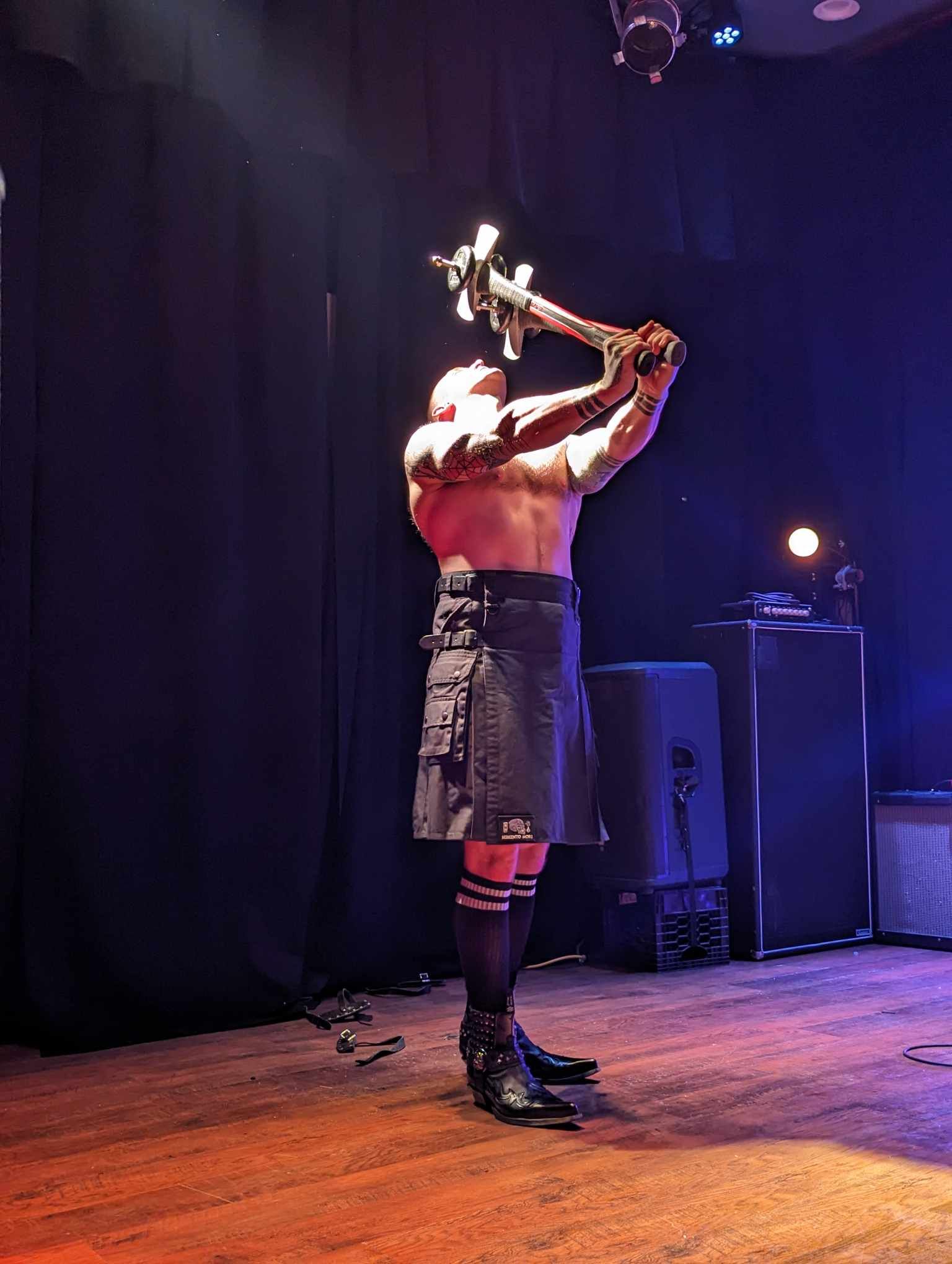 Reid Wilson sword swallowing on stage with dramatic theatrical lighting